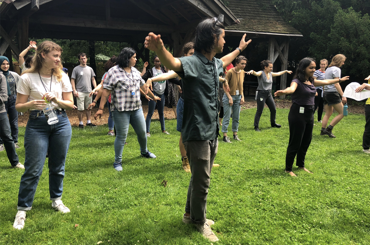 Adults standing in loose rows on a lawn, playing the compost shuffle game.