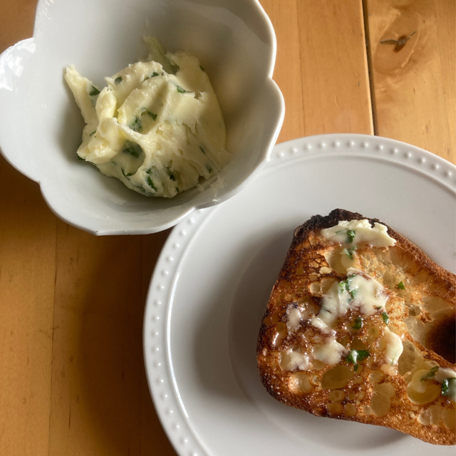 A bowl of fresh herb butter, and toast with butter.