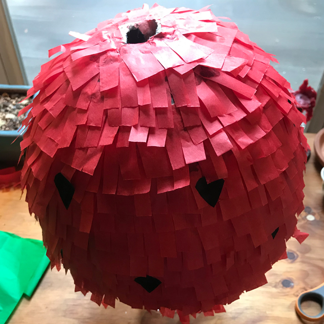 Balloon being decorated with strips of tissue paper.