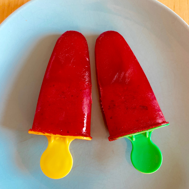 Finished frozen fruit popsicles on a plate.