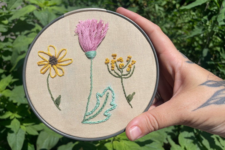  hand holding floral embroidery in embriodery loop 